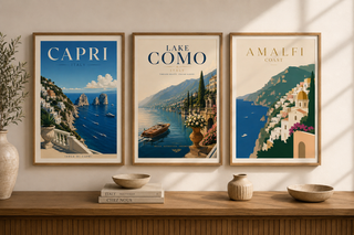 Three framed posters of scenic locations on a wall above a wooden shelf with decorative items.